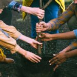 A diverse group working together to plant a tree, symbolizing teamwork and sustainability.